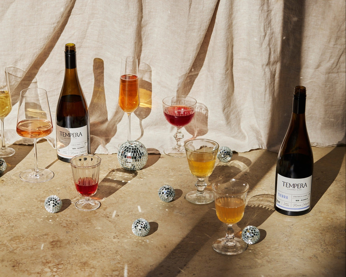 Tempera gourmet sips bottles and filled glasses on a wooden table with a neutral background